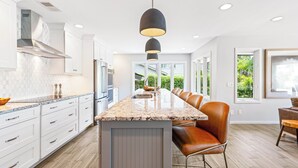 Una cocina moderna con armarios blancos, encimera de granito y una isla central con asientos.