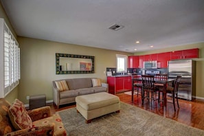 A living room with a sofa, ottoman, and a dining area with chairs and a table.