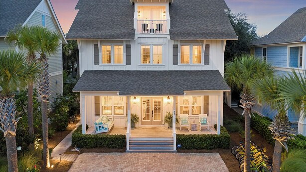 A two-story house with a balcony, a front porch with seating, and a driveway. - Driftwood - Vacation Home Near the Beach with a Large Outdoor Area (Santa Rosa Beach)
