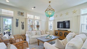 A spacious living room with a white sofa set, a wooden coffee table, and a large flat-screen TV. - Driftwood - Vacation Home Near the Beach with a Large Outdoor Area (Santa Rosa Beach)