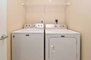 A laundry room with two Maytag washers and dryers, a white wall, and a door with a silver handle. - Updated appliances in beachfront condo w/private balcony! (Destin)