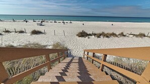 Een strand met een houten trap die naar het zand leidt, omringd door een hek.