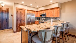 A kitchen with wooden cabinets, stainless steel appliances, and a marble countertop. - Crystal Peak Explorer Condo: Ski-In, Ski-Out Luxury (Breckenridge)