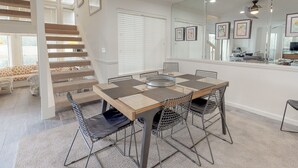 A dining area with a wooden table, metal chairs, and a ceiling fan. - Beautiful villa with lake views and a floating dock!  271F (Miramar Beach)
