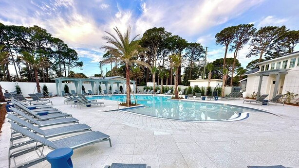 A pool area with sun loungers and palm trees. - Beautiful villa with lake views and a floating dock!  271F (Miramar Beach)