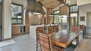 A modern kitchen with wooden cabinets, a large island, and hanging pendant lights. - Lonestar Lodge: Sweeping Mountain Views, Hot Tub & Patio (Breckenridge)
