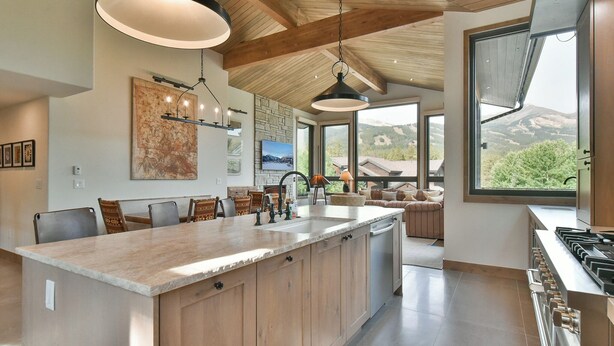 A modern kitchen with a large island, pendant lighting, and a view of the outdoors. - Lonestar Lodge: Sweeping Mountain Views, Hot Tub & Patio (Breckenridge)
