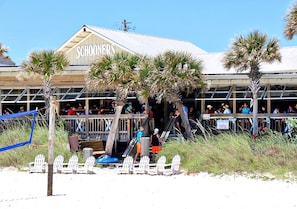 A beachside restaurant with outdoor seating and a covered entrance.