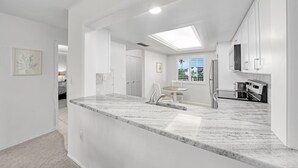 Una cocina moderna con encimera de mármol, electrodomésticos de acero inoxidable y tragaluz.