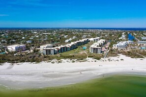 An aerial view of a coastal hotel with multiple buildings, a beach, and a marina.