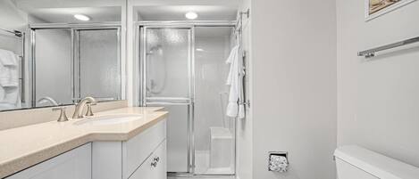 A modern bathroom with a shower, toilet, and sink.