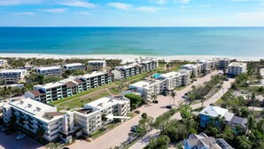 Un complejo hotelero frente al mar con varias construcciones, una playa y vistas despejadas del océano.