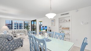 Una sala de estar moderna con comedor, ventanas amplias y vista al océano.