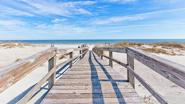 A wooden boardwalk leading to the beach with a clear sky. - Three Sisters | Home with Pool, Patio, Two Porches (Tybee Island)