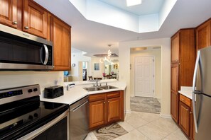 Una cocina moderna con armarios de madera, electrodomésticos de acero inoxidable y un tragaluz.