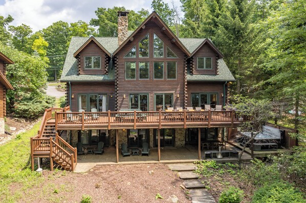 A log cabin with a deck, outdoor seating, and a stone chimney.