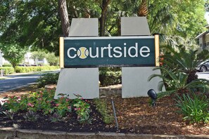 Courtside sign stands amidst a beautifully landscaped garden.