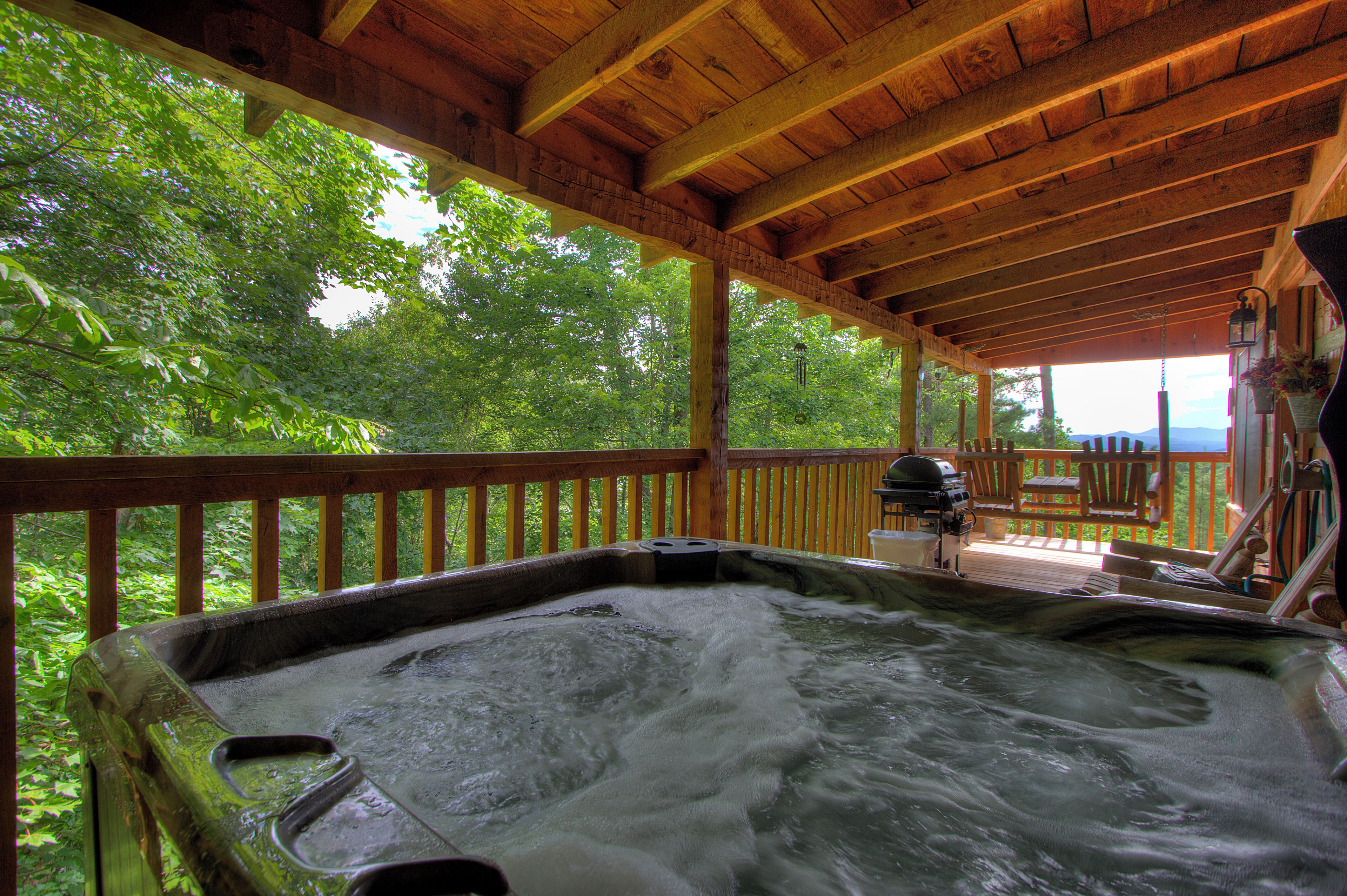 Ein Whirlpool mit einer Holzdiele und Blick auf üppiges Grün.