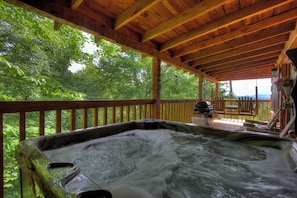 Un jacuzzi con una terraza de madera y vistas a un follaje exuberante.