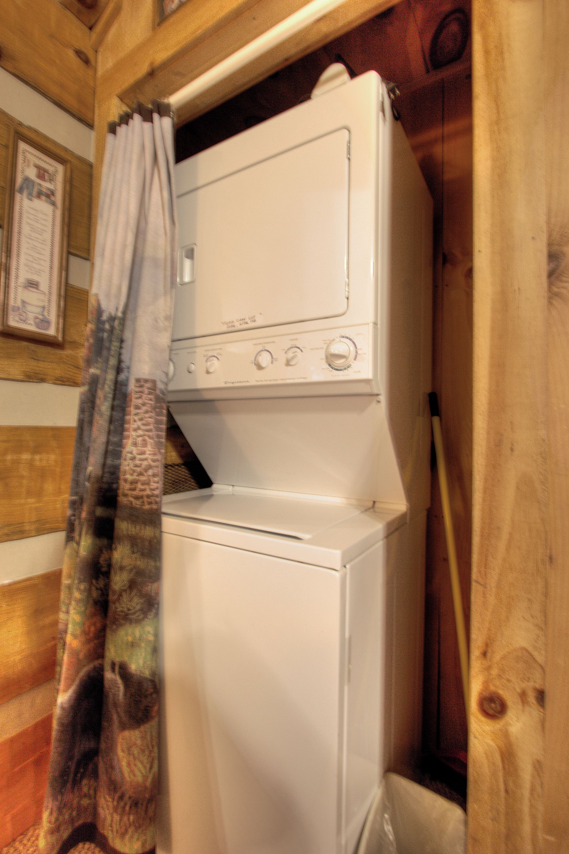 A white washing machine in a wooden room with a curtain.