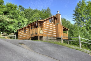 A wooden cabin with a porch, a chimney, and a signboard.