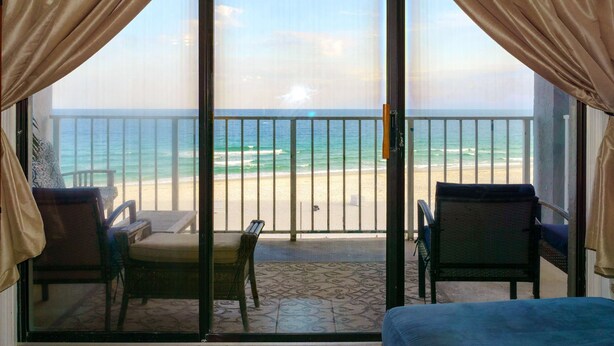 Ein Zimmer mit Meerblick, ein Balkon mit Stühlen und einem Tisch.