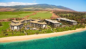 Ein Resort mit mehreren Gebäuden, einer Strandpromenade und einer Bergkulisse im Hintergrund.