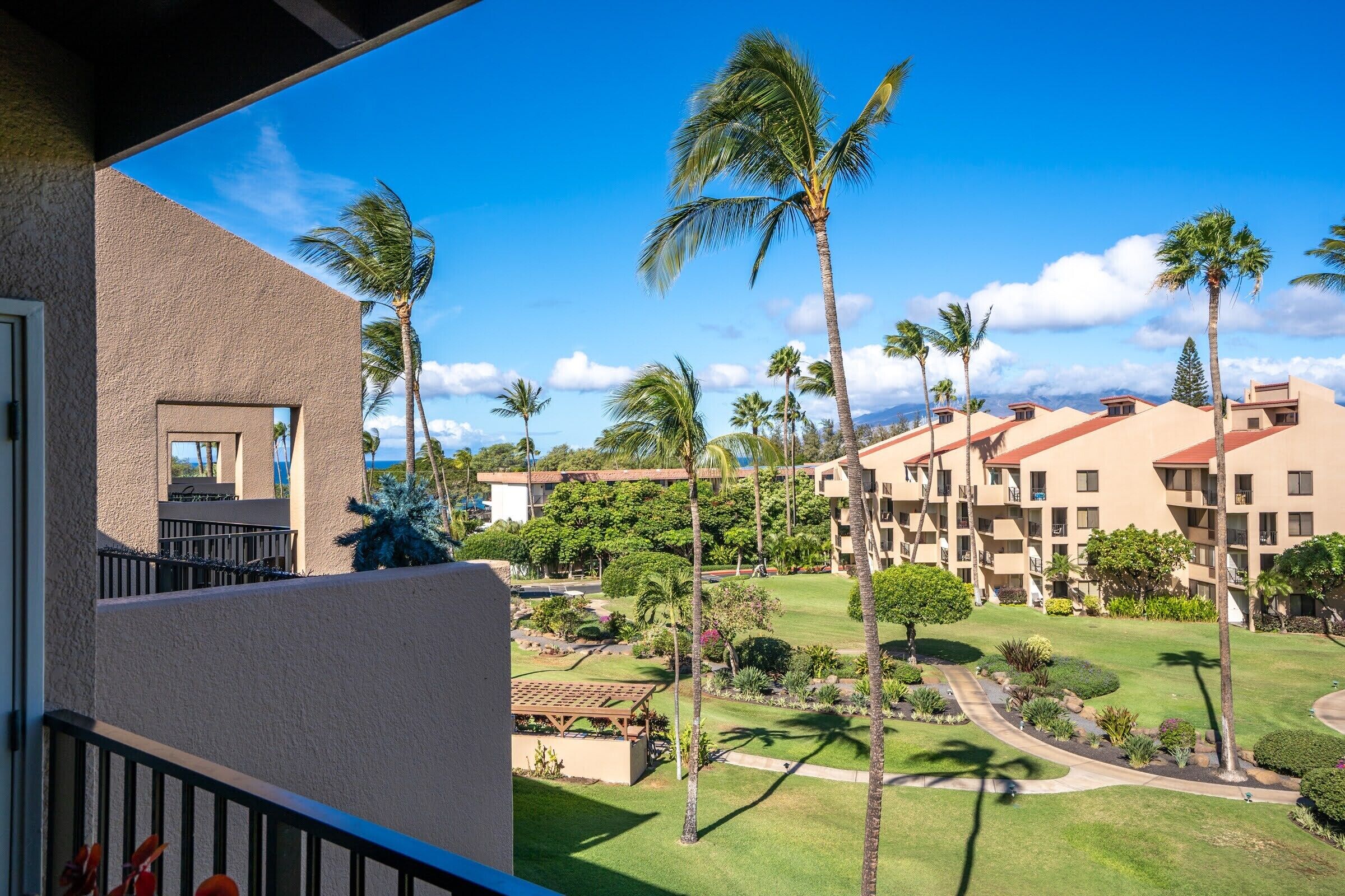 A resort with multiple-story buildings, palm trees, and a well-maintained lawn.