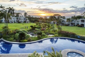 Un complexe hôtelier doté d’une piscine, d’une végétation luxuriante et offrant une vue imprenable sur le coucher de soleil.