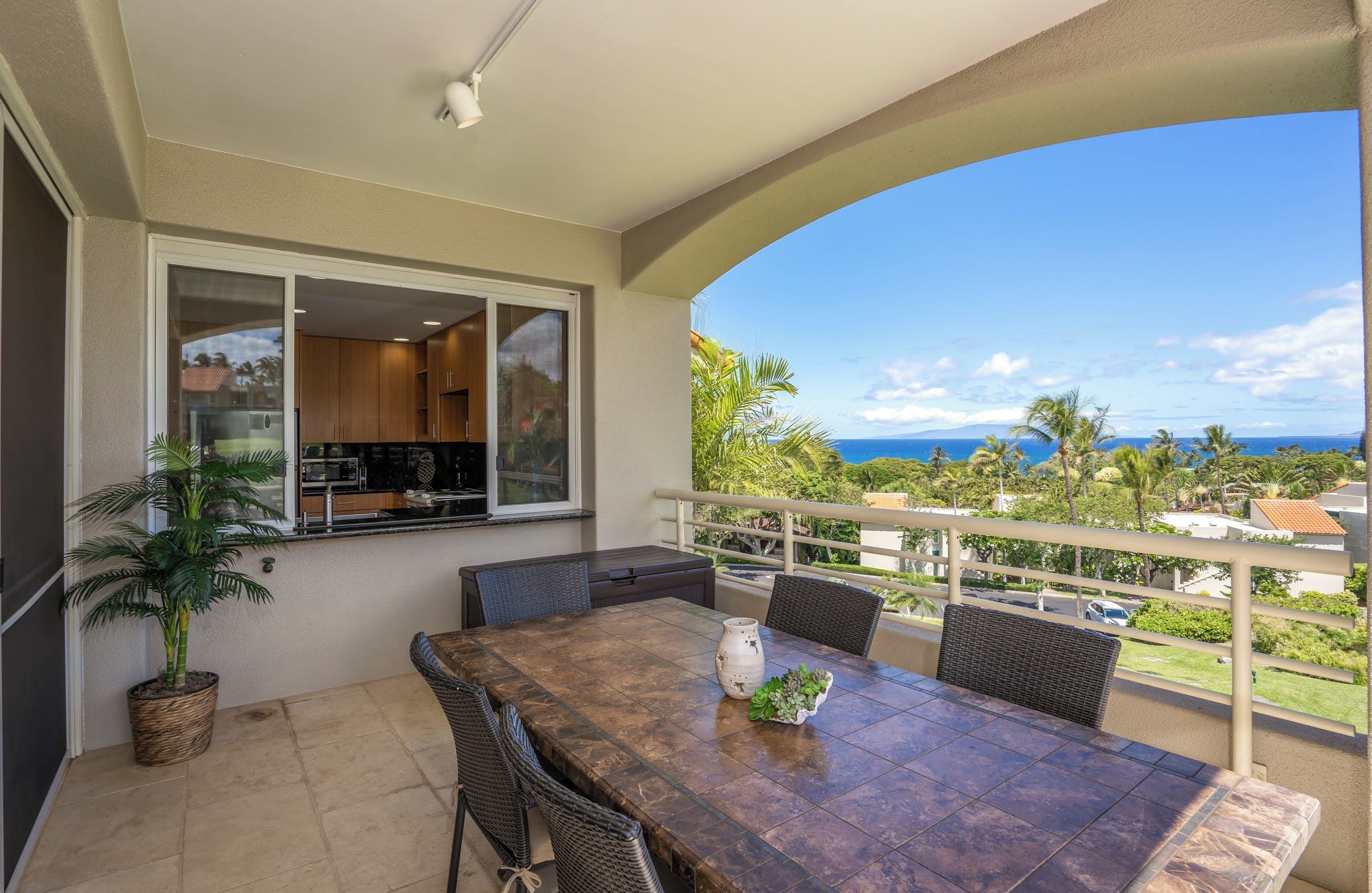 A balcony with a dining table, chairs, and a potted plant.