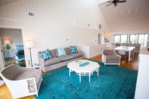 A spacious living room with a white ceiling fan, a grey sofa with patterned cushions, a white coffee table, and a blue rug. - Watervale - Gulf View, Pool, Gulf Trace neighborhood Grayton Beach (Santa Rosa Beach)