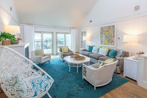 A spacious living room with a balcony, wicker furniture, and a large painting. - Watervale - Gulf View, Pool, Gulf Trace neighborhood Grayton Beach! (Santa Rosa Beach)