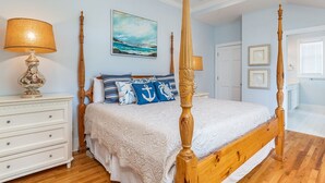 A four-poster bed with a white bedspread, a wooden headboard, and a nightstand with a lamp. - Marshview Hideaway | Pet Friendly, Marsh Views! (Tybee Island)