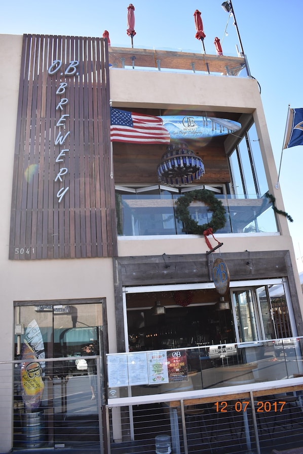 A modern building with a sign reading "O.B. BREWERY" and an American flag. - Ocean Beach Casita with hot tub, Ocean views & Garage! (San Diego)