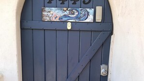 Eine dunkelblaue Tür mit der großen Nummer 4445 darüber und einem dekorativen Metallteil mit Wirbelmuster.