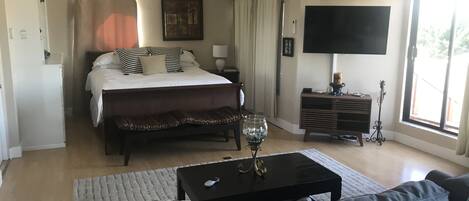 A bedroom with a bed, bedside table, lamp, and a TV.