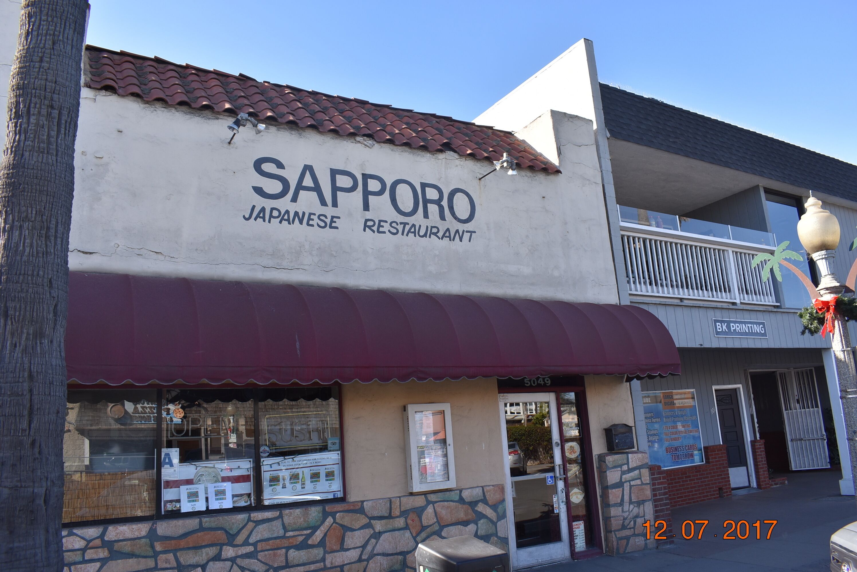 A Japanese restaurant named Sapporo with a stone facade and a red awning.