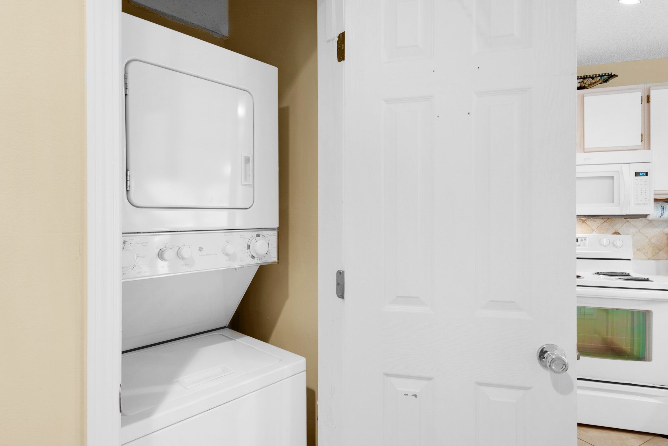 Une buanderie équipée d’un lave-linge et d’un sèche-linge, d’un four à micro-ondes et d’un four traditionnel.