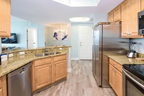 A modern kitchen with granite countertops, stainless steel appliances, wooden cabinets, and a built-in dishwasher. - Contemporary condo w/beach views from private balcony! (Destin)