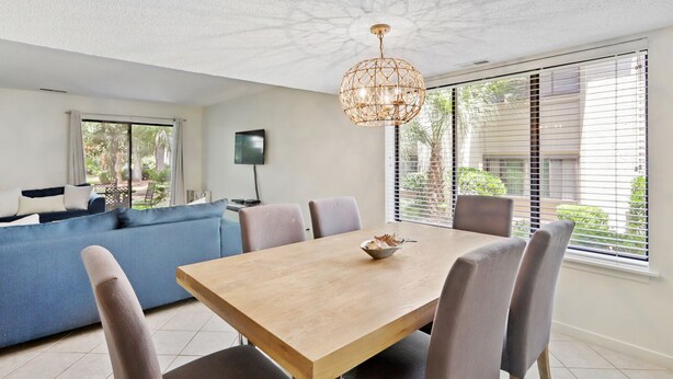 Een moderne eetruimte met een houten tafel, grijze stoelen en een bijzondere geweven hanglamp.