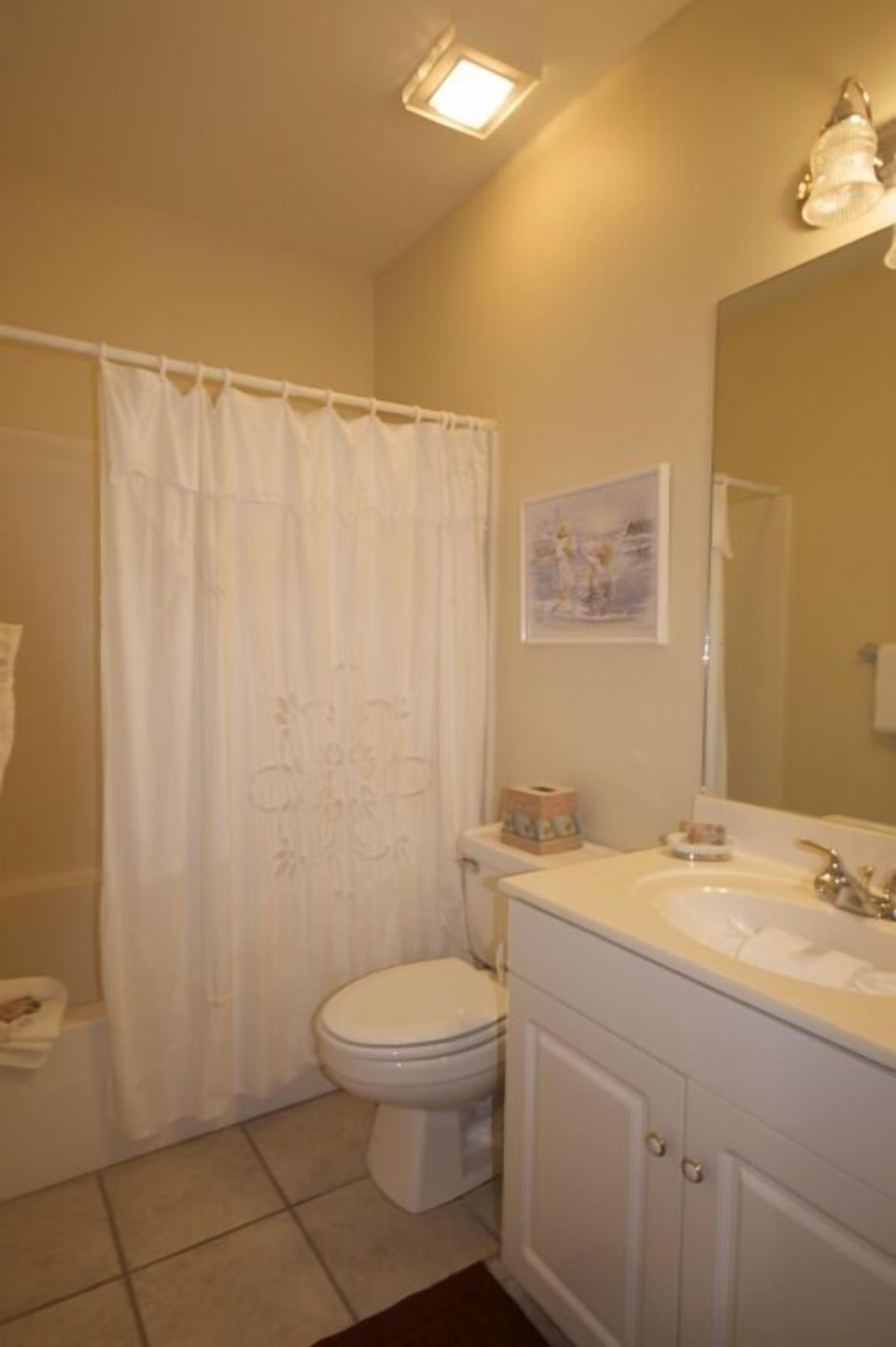 A bathroom with a toilet, sink, and shower curtain.