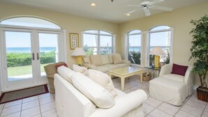 A spacious living room with a large window overlooking the ocean, a ceiling fan, and a potted plant. - Gulf front condo, 1st floor- walk out to beach, Pool, Santa Rosa beach (Santa Rosa Beach)
