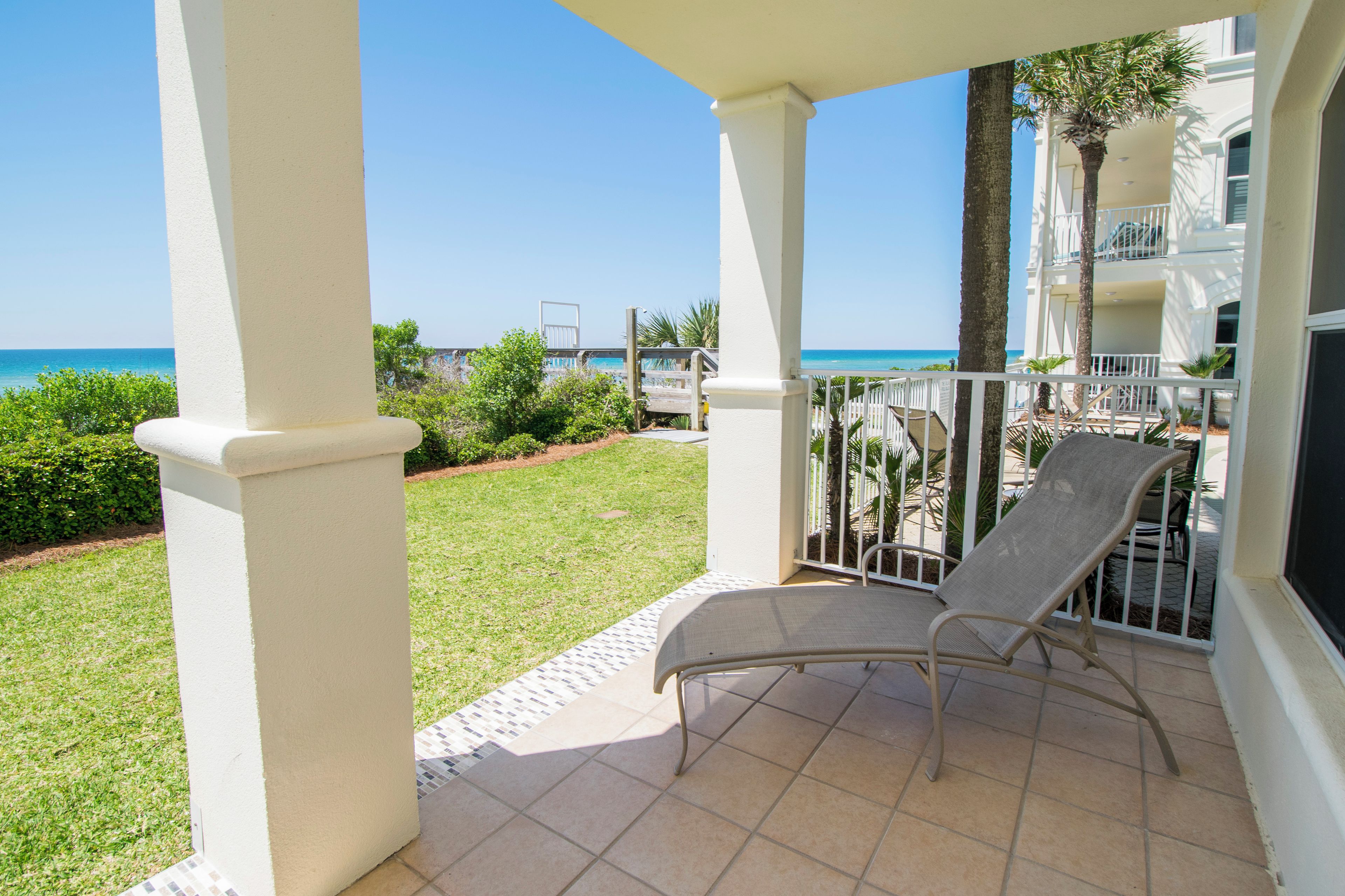 A balcony with a chair, a view of the ocean, and a building with a balcony.