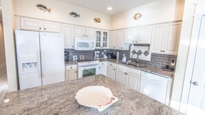 A modern kitchen with white cabinets, granite countertops, a refrigerator, microwave, stove, and dishwasher. - Gulf front condo, 1st floor- walk out to beach, Pool, Santa Rosa beach (Santa Rosa Beach)