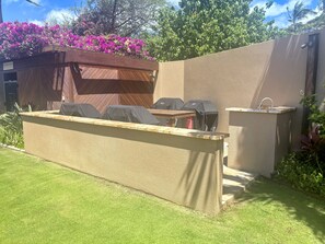 Een buitengebied met een barbecue, zitplaatsen en een spoelbak.