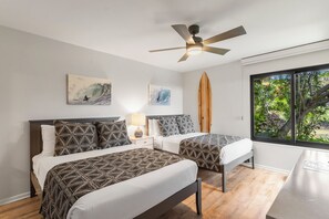A bedroom with two beds, a ceiling fan, artwork, and a window with a view of greenery. - Exquisite Escape: Elegantly Renovated Wailea Elua 801 – Tranquil Paradise (Wailea, Maui)