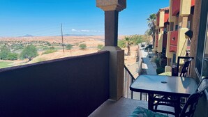 A balcony with a table and chairs, overlooking a desert landscape with distant mountains. - Crow's Nest by Mesquite Vacation Rentals: Stunning Views of Mesquite and $510 in free daily activities (Mesquite)