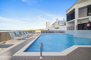 A swimming pool with lounge chairs, a deck, and a building with a sign indicating no diving. - Broadmoor 105 by Liquid Life (Orange Beach)