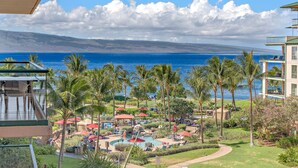 A resort with a pool area, palm trees, and a view of the ocean. - Maui Resort Rentals: Honua Kai Konea 515 - Upgraded 5th Floor Oceanview Studio (Lahaina)