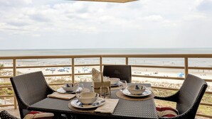 Een eettafel met stoelen en uitzicht op het strand.